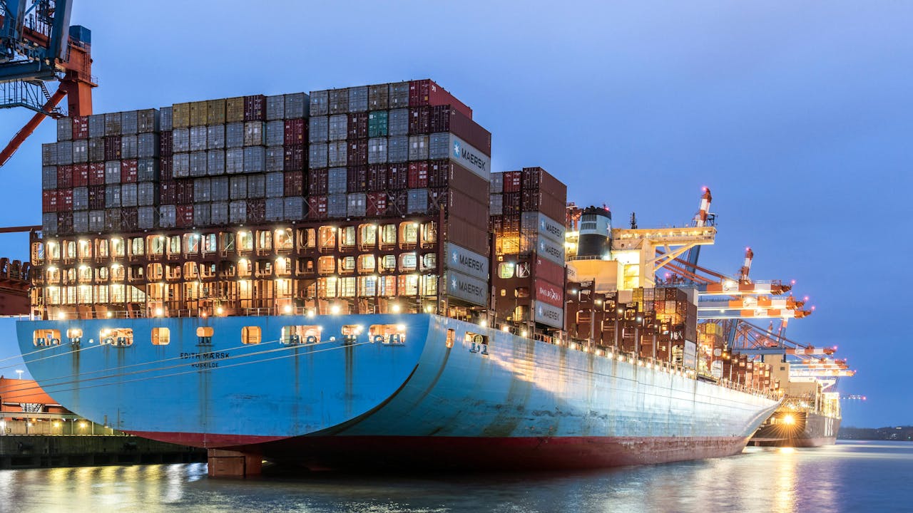 A huge cargo ship moored in Hamburg's harbor during the evening, showcasing global logistics.